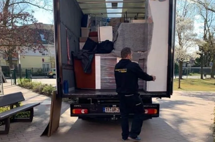 umzugshelfer laedt verpackte moebel in umzugswagen
